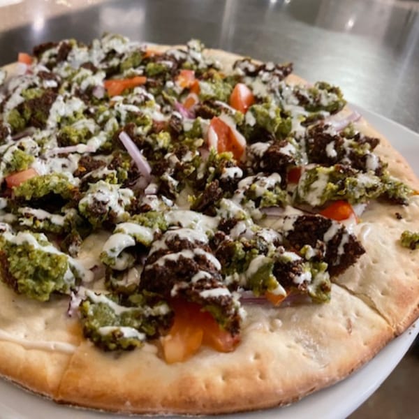 Lebanese flatbread topped with falafel, tomatoes, onions, and a drizzle of white sauce.