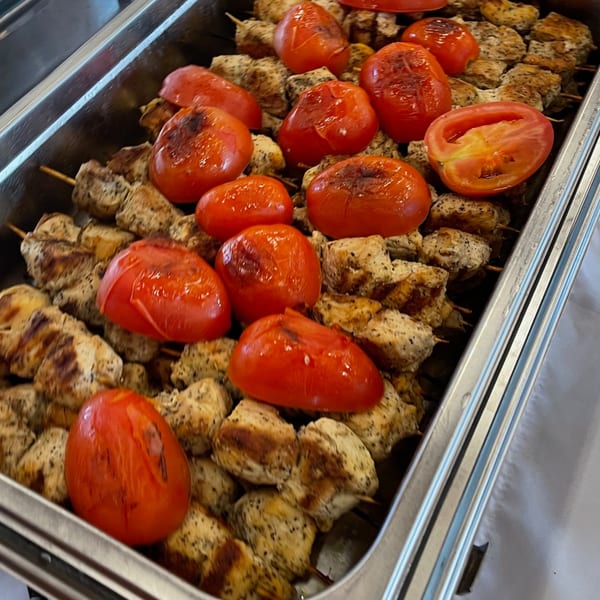 Lebanese chicken shish tawook skewers with grilled tomatoes in a metal serving tray.